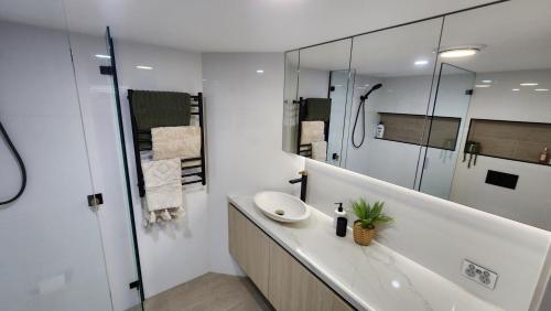 Un baño blanco con lavabo y espejo. en Cerulean Apartments, en Caloundra