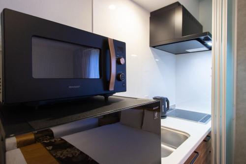 eine Mikrowelle auf einer Theke in einer Küche in der Unterkunft HOTEL YeeT Tenjin Minami in Fukuoka