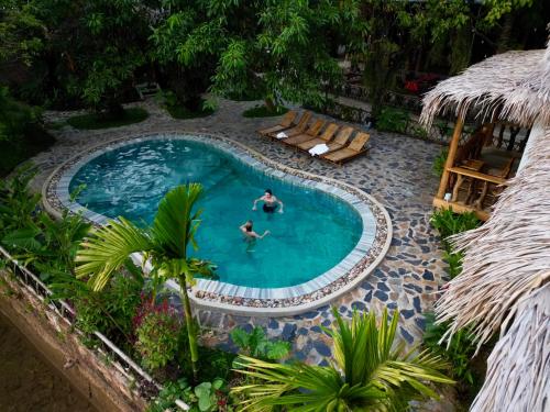 2 personnes nagent dans une piscine dans l'établissement Coconut Minh Tho Homestay, à Mai Châu