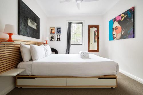 a bedroom with a large white bed and some pictures at Darlington Hideaway - Close to everything in Sydney