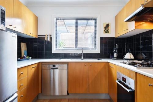 a kitchen with wooden cabinets and a sink and a window at Darlington Hideaway - Close to everything in Sydney