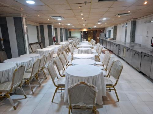 une rangée de tables et de chaises blanches dans une pièce dans l'établissement فندق مشرق كدي, à La Mecque