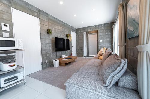 a living room with a couch and a tv at Hale Twelve AB in Miyako-jima