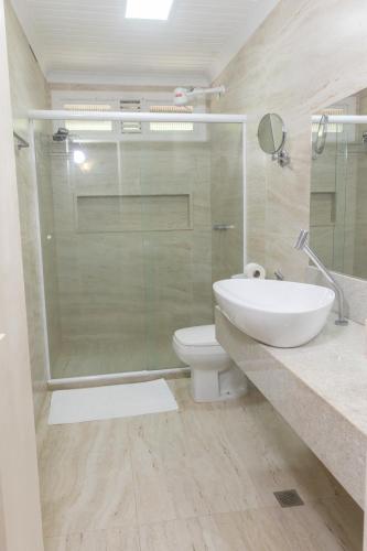a bathroom with a toilet and a glass shower at Hotel Karapitangui in Morro de São Paulo