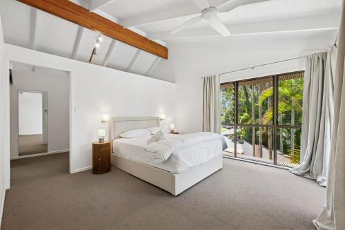 Noosa Retreat. Ocean Views, Pool and Serenity في نوسا هيدز: غرفة نوم بيضاء مع سرير ونافذة كبيرة