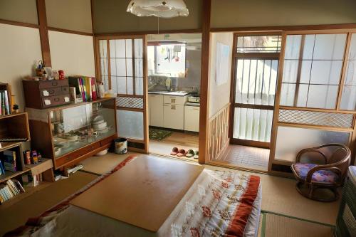 a living room with a table and some windows at 八戸ゲストハウス トセノイエ / Hachinohe Guest House Tosenoie in Hachinohe