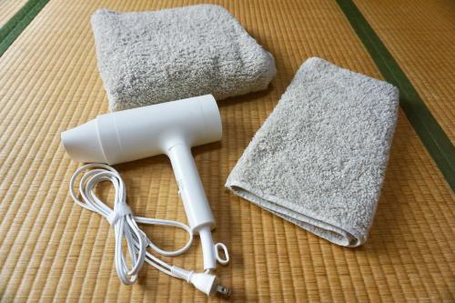 a white hair dryer and two mats on a table at 八戸ゲストハウス トセノイエ / Hachinohe Guest House Tosenoie in Hachinohe