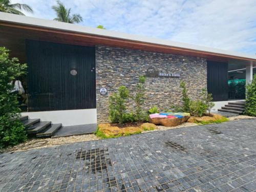 un edificio de ladrillo con una puerta y algunas plantas en Khanom Station 549, en Ban Na Dan