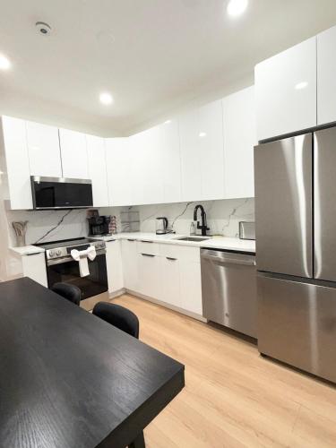 a kitchen with white cabinets and a stainless steel refrigerator at The View - Direct Bus Time Square NYC Breakfast Included - A in Jersey City