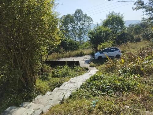 a white car parked on a dirt road at Pinewood Retreat in Bilāspur