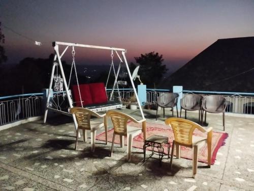a group of chairs and a swing on a balcony at Pinewood Retreat in Bilāspur