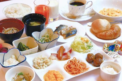 a table with plates of food and bowls of food at Hotel Yamagata Hills Ekimae Odori in Yamagata