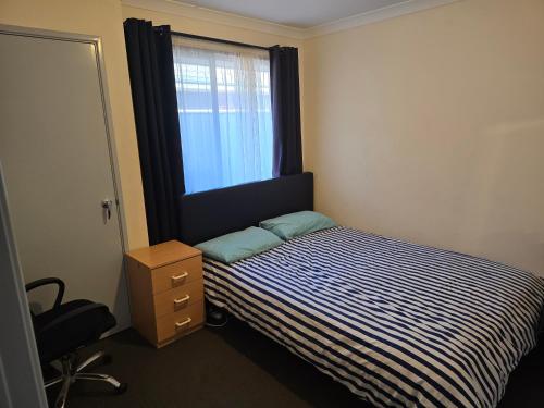 a small bedroom with a bed and a window at R n M Guest House in West Swan