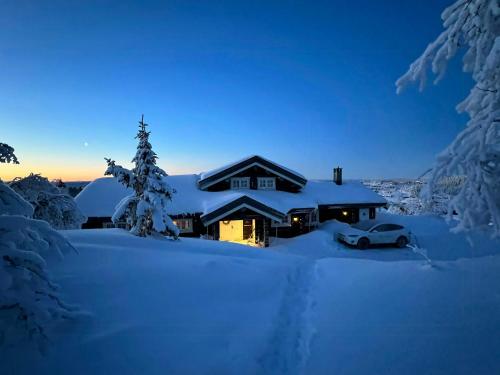 una casa cubierta de nieve con un coche delante en Family Cabin With Panoramic Views In Aurdalsåsen, en Aurdal