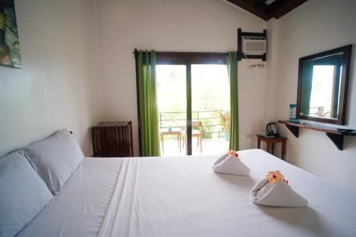 ein Schlafzimmer mit einem weißen Bett mit zwei Blumen darauf in der Unterkunft Point 303 Resort in General Luna