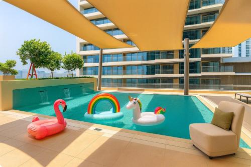 a swimming pool with three inflatable swans and a rainbow at Pure Voyage Beachfront in Dubai
