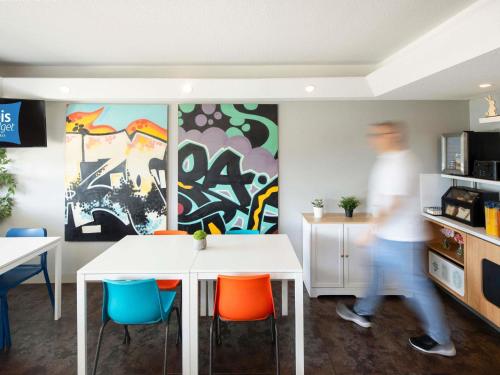 ウェントワースビルにあるアイビス バジェット ウェントワースヴィルのテーブルと椅子のあるダイニングルームの前を歩く男性