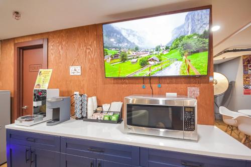 ニューヨークにあるJG Time Hotel by JGSTAY, Times Squareのカウンターの電子レンジ、壁掛けテレビ付