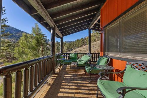 a deck with green chairs and a view of the mountains at Cabin 9- Spacious cabin- 4 King beds- 2 baths in Estes Park