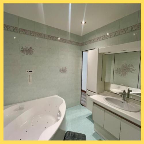 une salle de bains avec baignoire et lavabo dans l'établissement Magnifique T3 spacieux de 150 m carrés Vue Lac Léman, à Évian-les-Bains