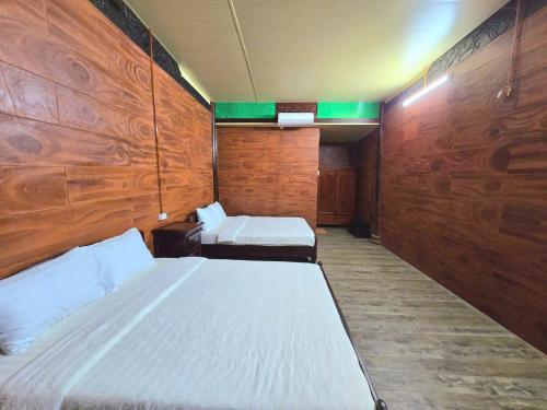 Làng Du Lịch Sinh Thái Đá Nổi في Phong Ðiền: غرفة بسريرين وجدران خشبية