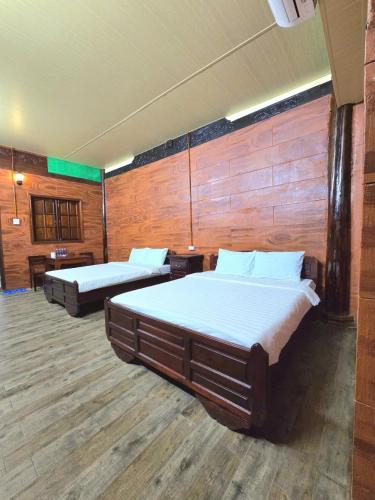 Làng Du Lịch Sinh Thái Đá Nổi في Phong Ðiền: سريرين في غرفة كبيرة بجدران خشبية