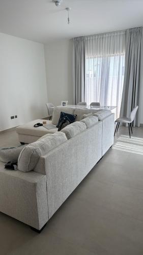 a white living room with a large couch in front of a window at Noya Viva villa in Abu Dhabi