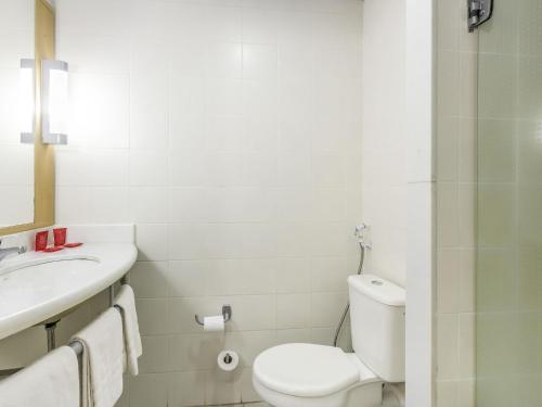 a white bathroom with a toilet and a sink at ibis Barretos in Barretos