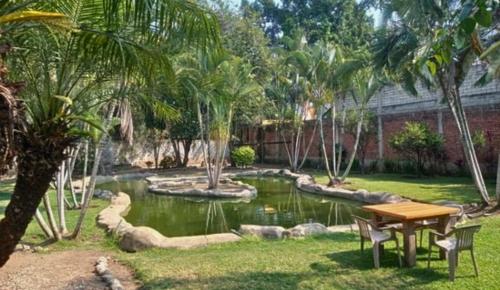 a garden with a pond and a table and chairs at Lago24 Habitaciones in Cocoyoc