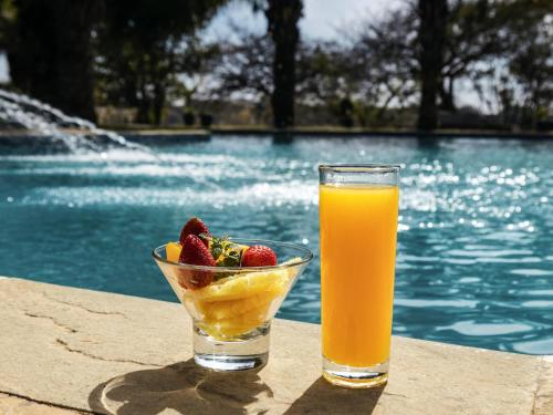 ルブンバシにあるPullman Lubumbashi Grand Karavia.の- プールサイドのオレンジジュース1杯とフルーツ1杯