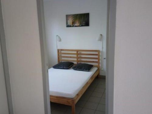 une petite chambre avec un lit avec deux oreillers dessus dans l'établissement Gîte avec Terrasse et Salon de Jardin - API-1-52-592, à Dévillac