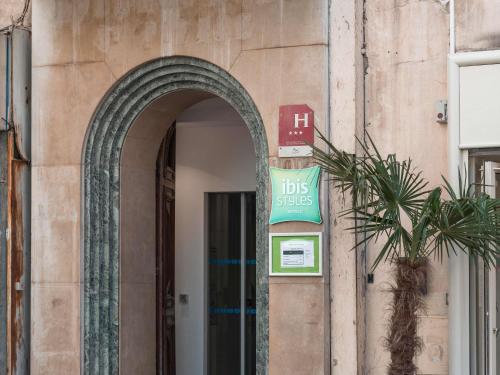 une arche sur le côté d'un bâtiment avec un panneau dans l'établissement ibis Styles Marseille Vieux Port, à Marseille