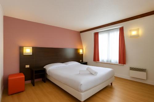 a bedroom with a large white bed and a window at Hotel Arc Paris Porte d'Orléans in Montrouge