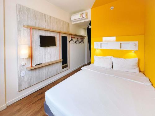 una camera con un letto bianco e una parete gialla di ibis budget Barbacena a Barbacena