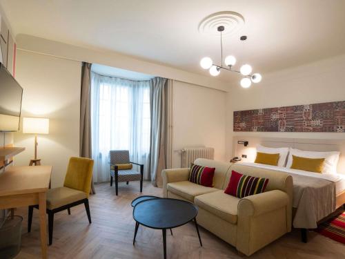 a hotel room with a large bed and a couch at Mercure Belgrade Excelsior in Belgrade