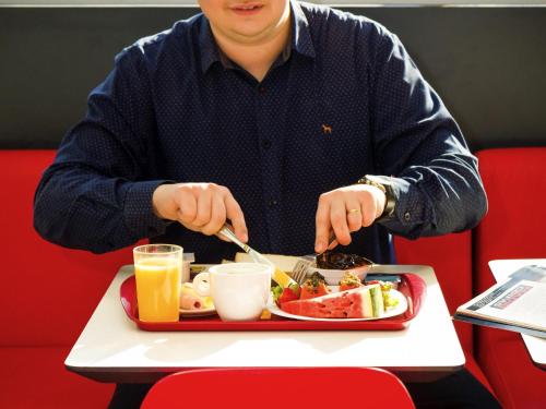 Un uomo seduto a un tavolo con un vassoio di cibo di ibis Marilia a Marília