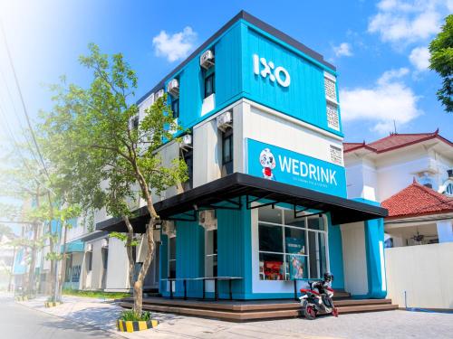 ein blau-weißes Gebäude mit einem Roller davor in der Unterkunft IXO Hotel Semarang in Stasiun Tawang