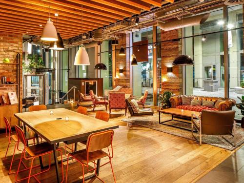 a living room with a couch and tables and chairs at ibis London Canning Town in London