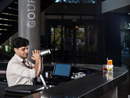 a man sitting at a bar with a microphone at Novotel Sorocaba in Sorocaba