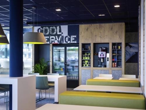 a restaurant with tables and chairs and a sign that reads cool service at ibis budget Rotterdam The Hague Airport in Rotterdam