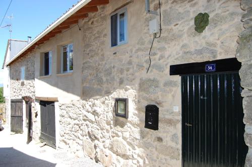 een stenen gebouw met een zwarte deur aan de zijkant bij Casa de las Flores Sober Ribeira Sacra in Sober