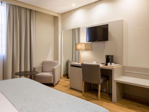 a hotel room with a bed and a desk and chair at Mercure Carlton Rioja in Logroño