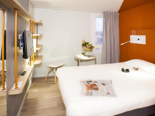 a hotel room with a bed and a newspaper on it at ibis budget Bordeaux Est Lormont in Lormont