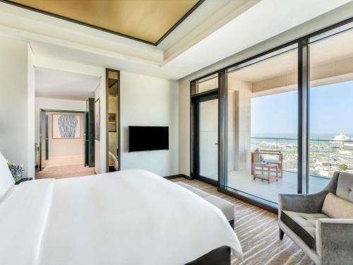 a bedroom with a large white bed and a large window at Alwadi Hotel Doha - MGallery Collection in Doha