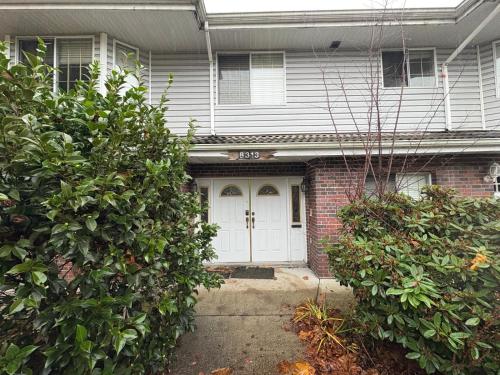a house with a white door and two bushes at North Delta Guest House - Scott Rd & Rapid Transit - Airport 20 Min - Free Parking & Fast Wi-Fi in Delta