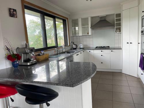 亚历山德拉Central Otago Farmlet的厨房配有白色橱柜和花岗岩台面