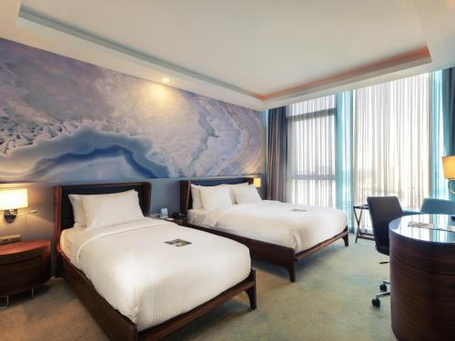 a hotel room with two beds and a painting on the wall at Mercure Istanbul Umraniye in Istanbul