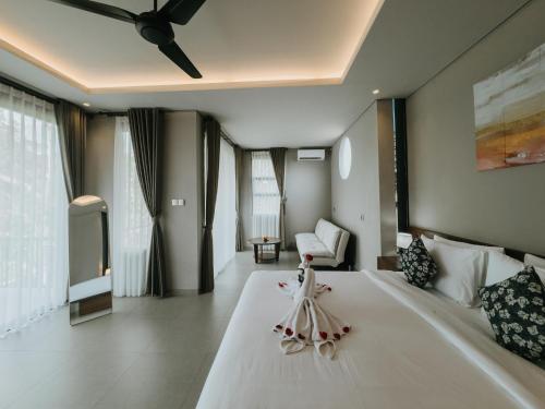 a bedroom with a large white bed with a ceiling at Nusari Villa Ubud in Ubud