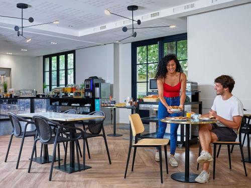 uma mulher ao lado de um homem sentado à mesa em Adagio Serris Val d'Europe em Serris