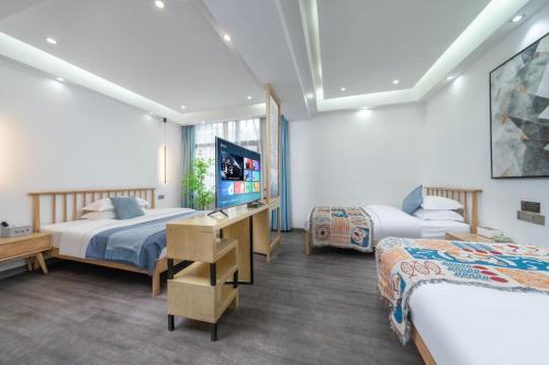 een hotelkamer met twee bedden en een tv bij Phoenix Geometry Light Accommodation in Fenghuang
